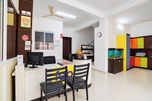 Uma área de recepção com balcão, cadeiras, computador e um aquário.