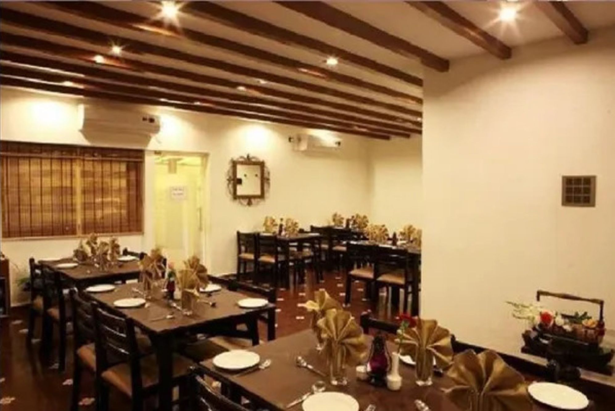 Un comedor con varias mesas listas para el servicio, vigas de madera en el techo y una puerta con un letrero.