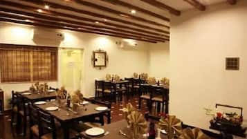 Un comedor con varias mesas listas para el servicio, vigas de madera en el techo y una puerta con un letrero.