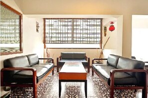 Un salón con sofá, una mesa de centro y un ventanal con rejas de metal.