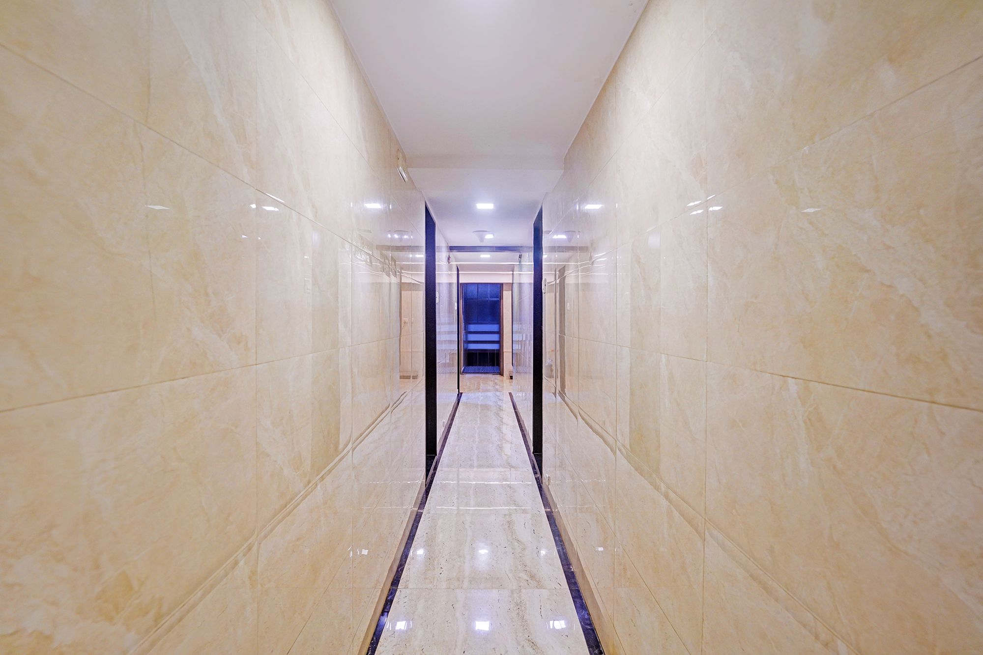A corridor with reflective marble walls and a central strip leading to a staircase.