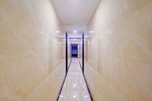 A corridor with reflective marble walls and a central strip leading to a staircase. - FabHotel Qamar (Mumbai)