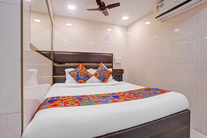 A hotel room with a bed, a ceiling fan, and an air conditioning unit.