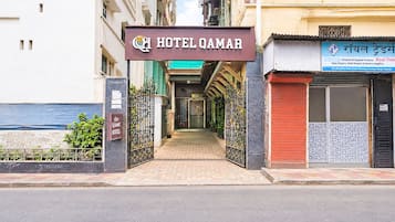 Der Eingang zum Hotel Qamar, mit einem Schild über der Tür, einem verschlossenen Weg und einem Geschäft mit einem Schild in einer Fremdsprache auf der rechten Seite.
