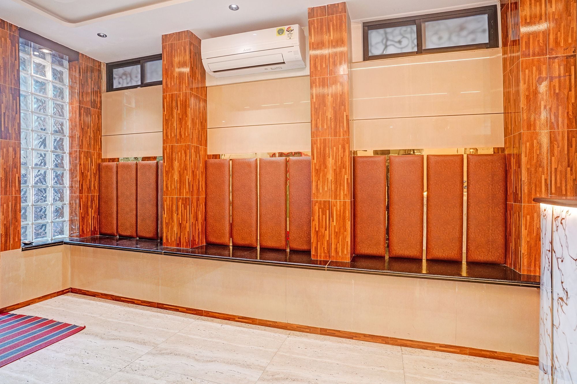 A hotel room with a seating area, a large window with a view, and an air conditioning unit.