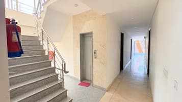 A hotel hallway with a staircase, a door, and a red mat at the bottom.