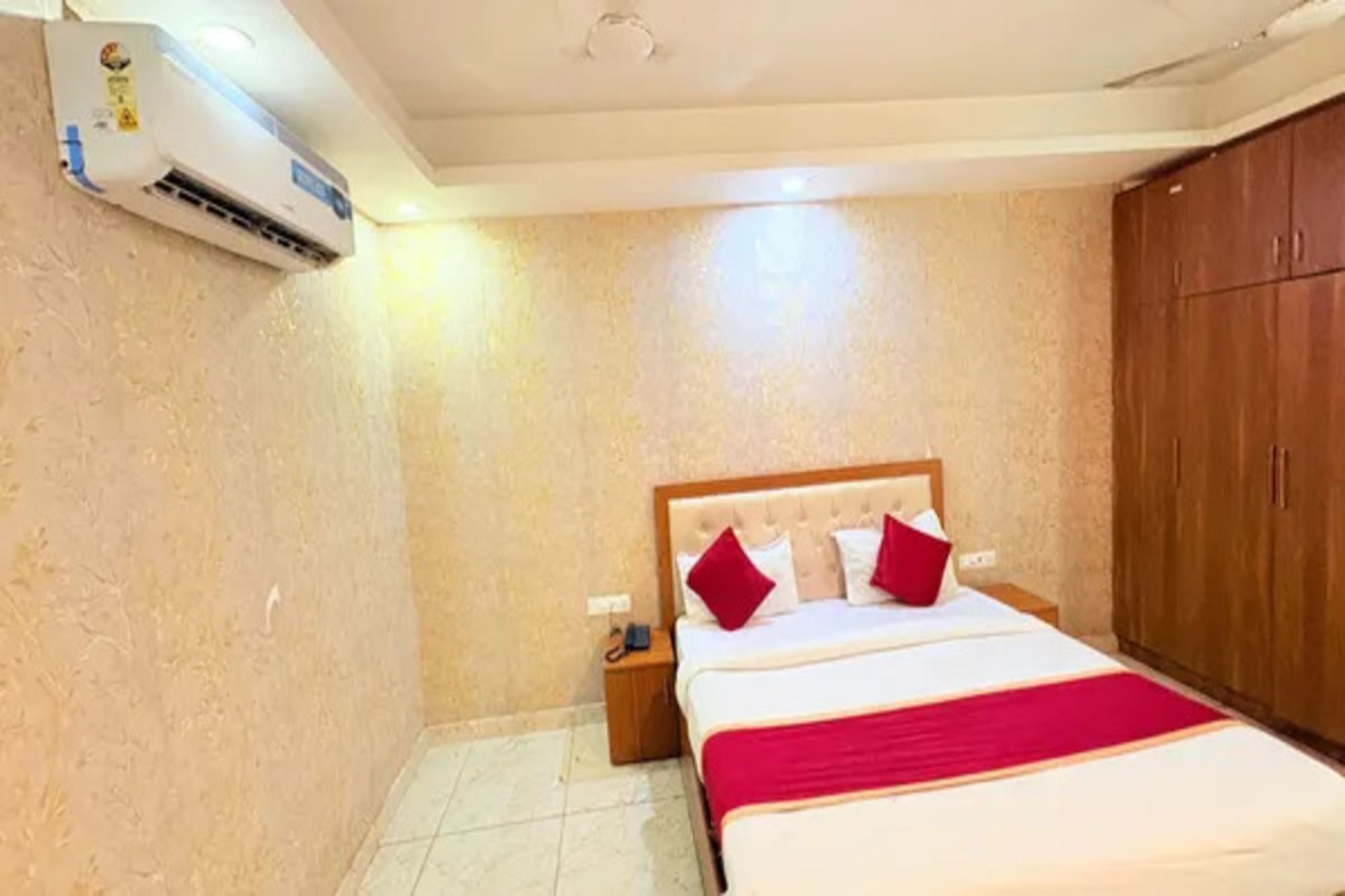 Una habitación de hotel con una cama, una mesita de noche, un equipo de aire acondicionado y un armario.