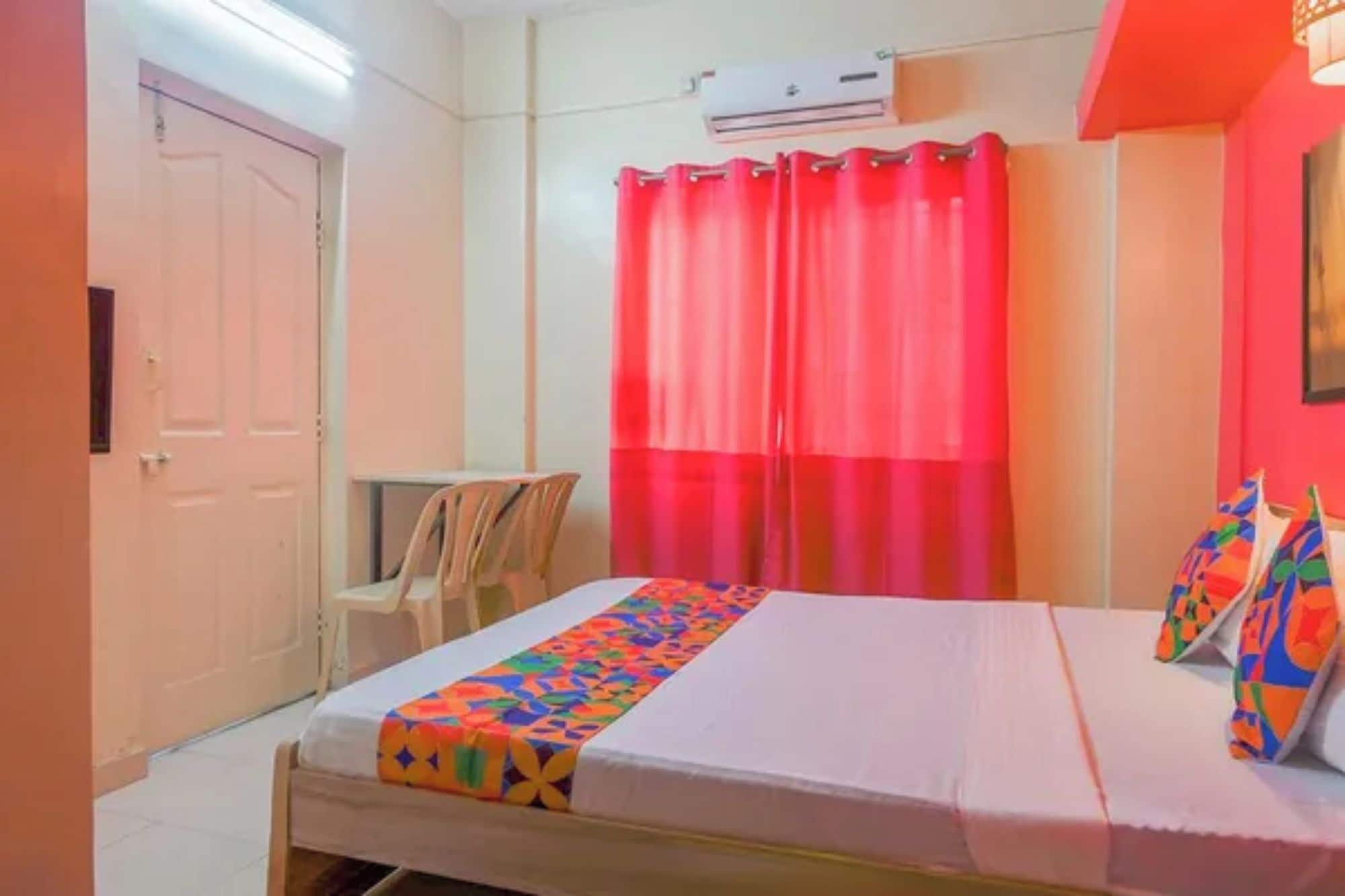 A bedroom with a bed, a chair, a desk, and a window with curtains.