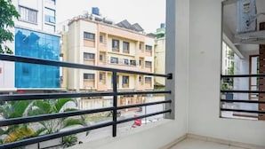 Un balcón con baranda de metal, vista de un edificio residencial y cielo despejado.