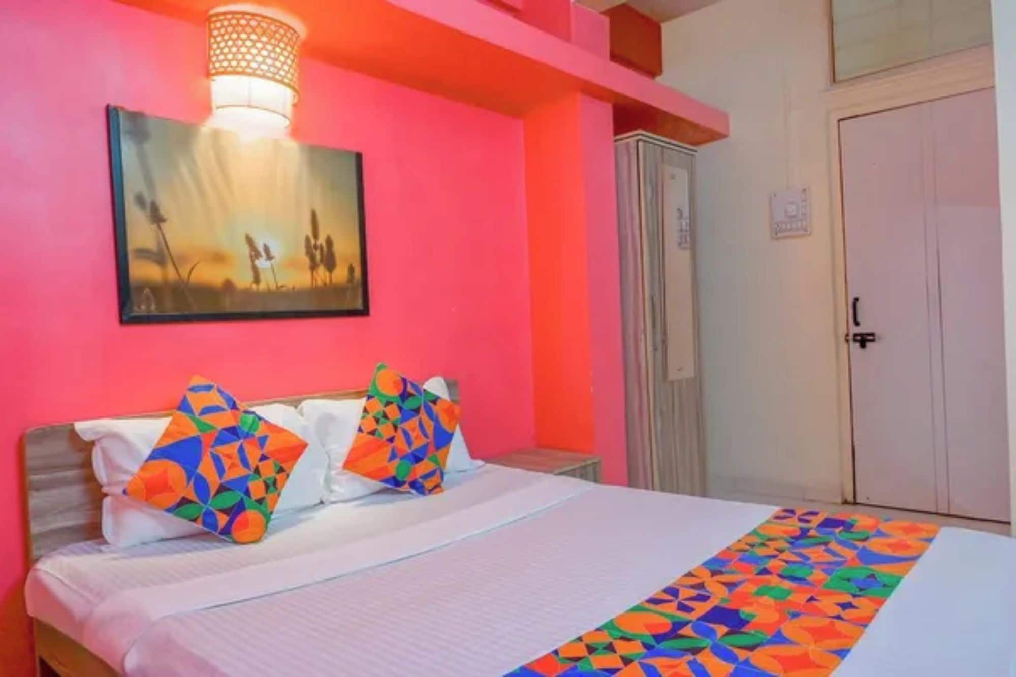 Una cama con almohadones geométricos coloridos, una colcha blanca y un corredor con estampado.