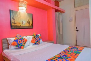 A bed with colorful geometric pillows, a white bedspread, and a patterned runner. - FabHotel Saraswati Niwas (Pune)