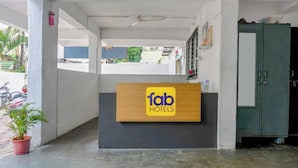 Una recepción con un cartel de Fab Hotels, una planta en maceta y un armario verde.