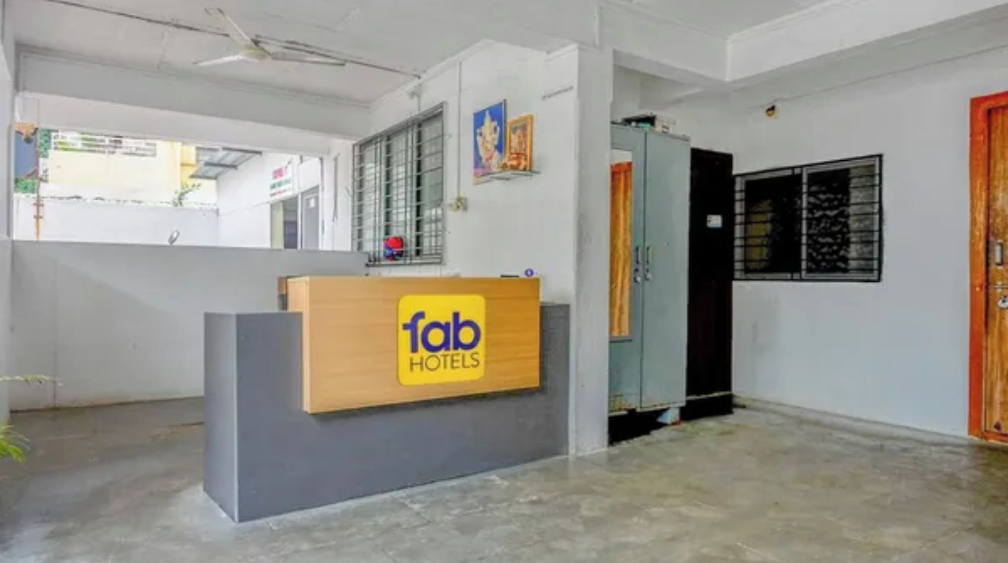 Una recepción con un cartel que dice 'fab hotels', una ventana con barrotes de metal y una puerta con marco de madera.