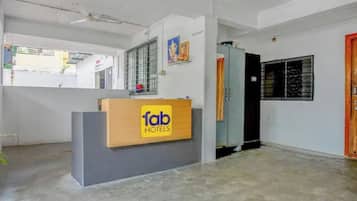 Una recepción con un cartel que dice 'fab hotels', una ventana con barrotes de metal y una puerta con marco de madera.