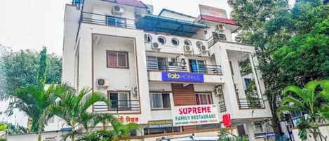 Un immeuble à plusieurs étages abritant un restaurant familial appelé « Supreme » et un hôtel appelé « Fab Hotels ».