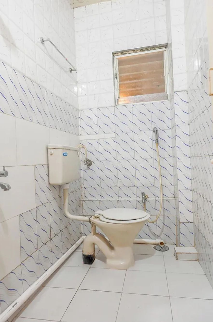 A small, tiled bathroom with a toilet, a shower, and a window.