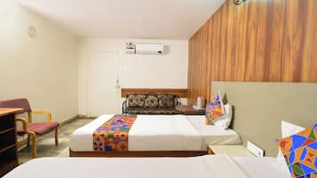Een hotelkamer met twee bedden, een slaapbank, een bureau en een airconditioning.