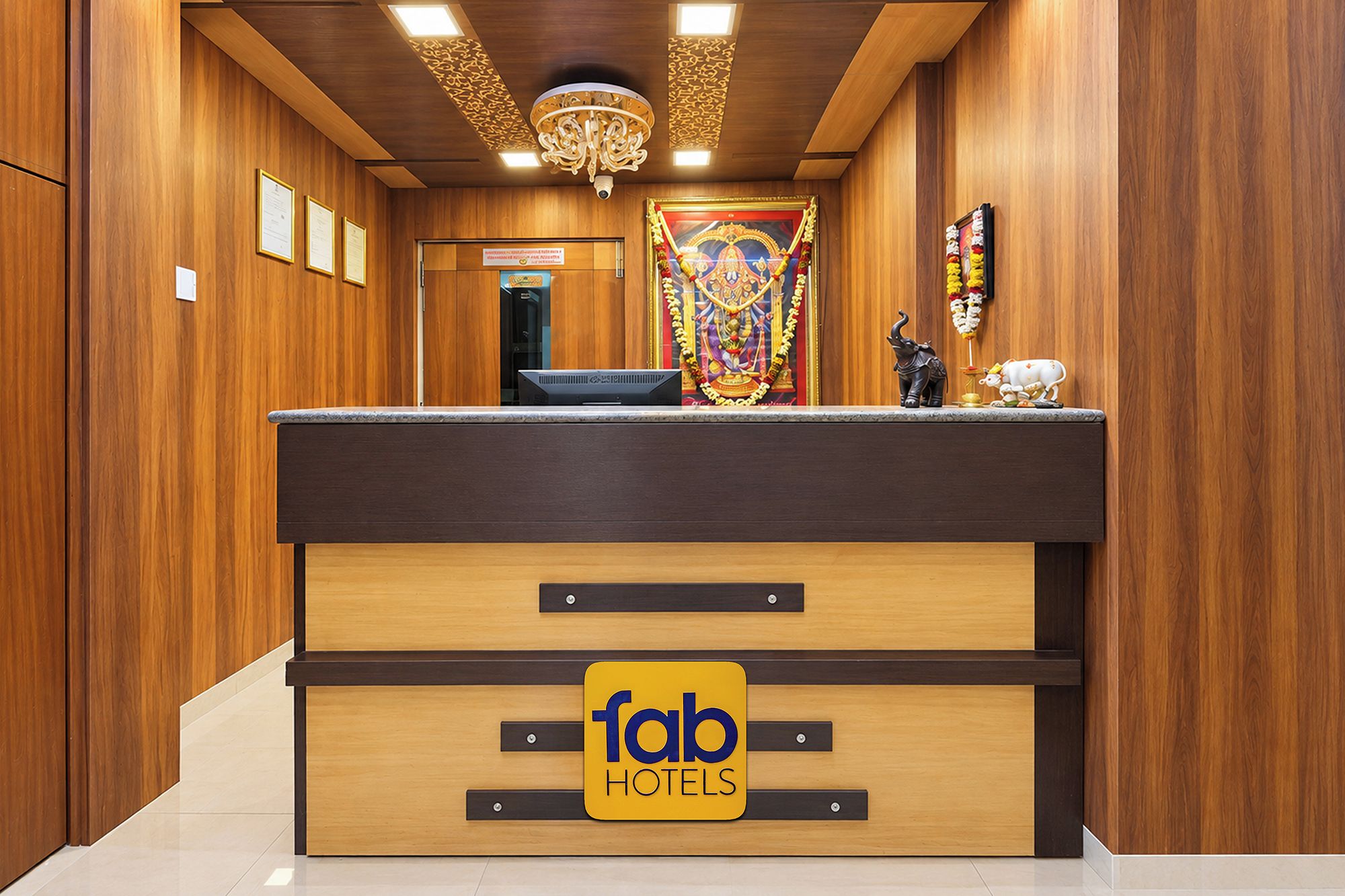 Un mostrador de recepción con el logotipo de 'fab hotels' y una estatua de una divinidad.