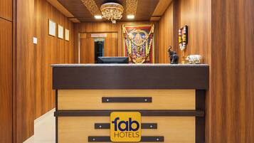 Un mostrador de recepción con el logotipo de 'fab hotels' y una estatua de una divinidad.