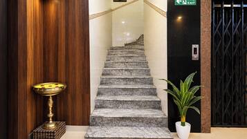 Una escalera con un letrero de salida de incendios, una planta en maceta y una lámpara de bronce.
