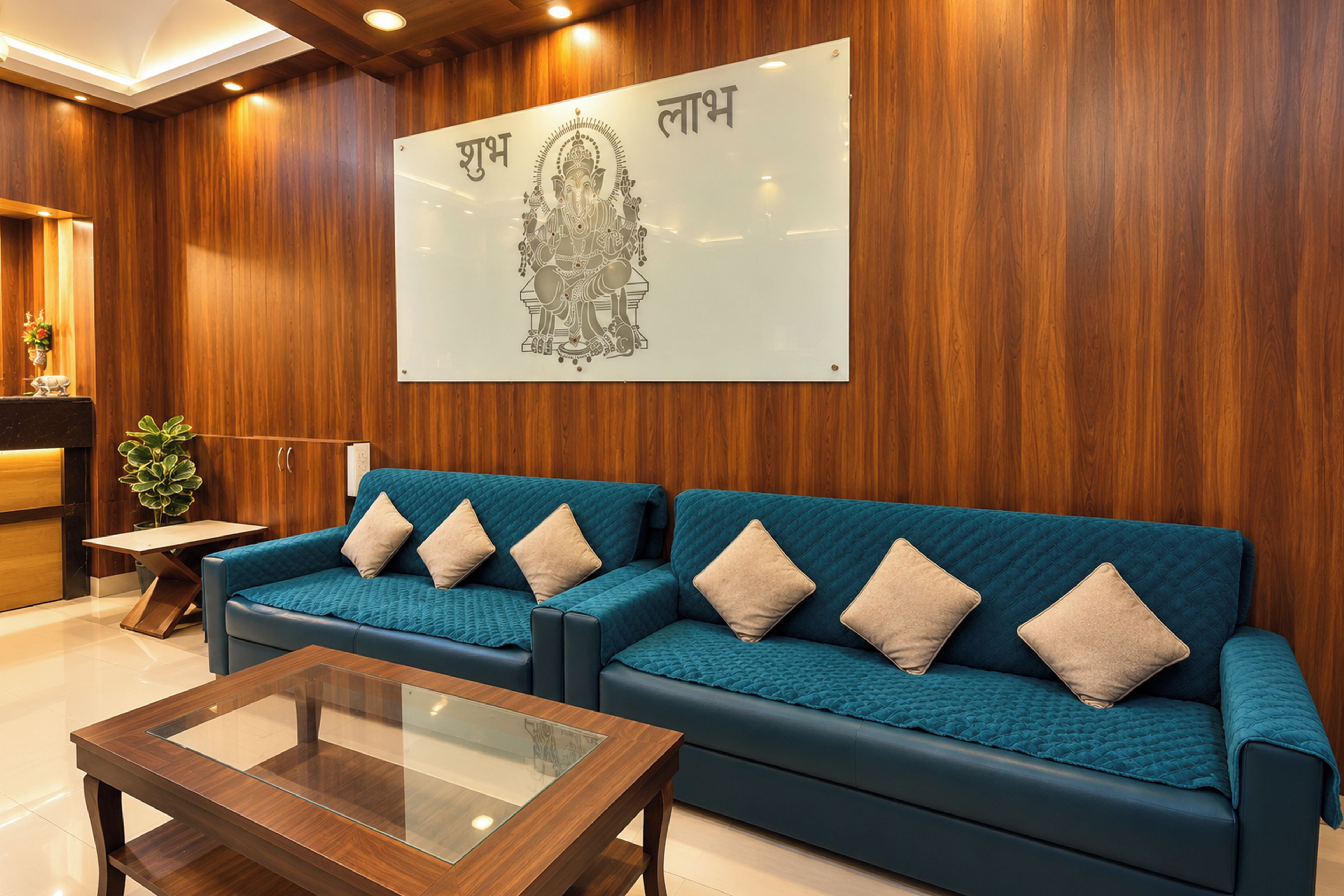Zona de recepción con pared de madera, mostrador de recepción, sofá azul con cojines beige y una mesa de centro de vidrio.