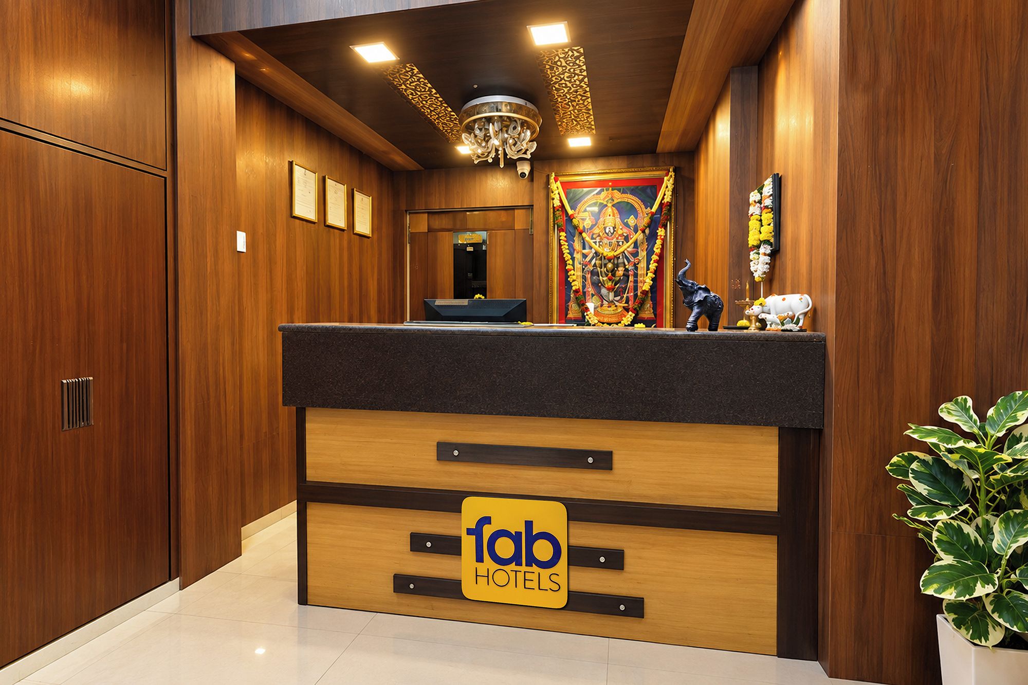 A reception desk with a 'fab hotels' sign, wooden paneling, a chandelier, and a decorative altar with flowers.