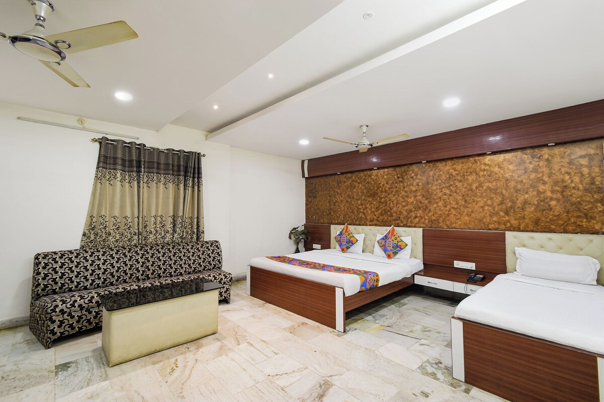 Una habitación de hotel con una cama, un sofá, una mesita y un ventilador de techo.