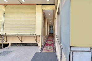 Un pasillo con una puerta con persiana cerrada, un suelo estampado y una barandilla de metal.