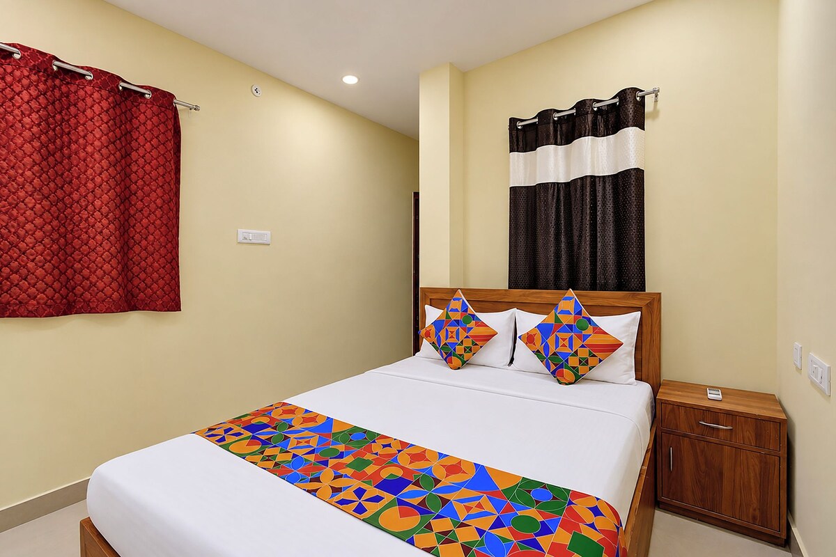 Una habitación de hotel con una cama, una mesita de noche, un armario de madera, una cortina roja y un equipo de aire acondicionado instalado en la pared.