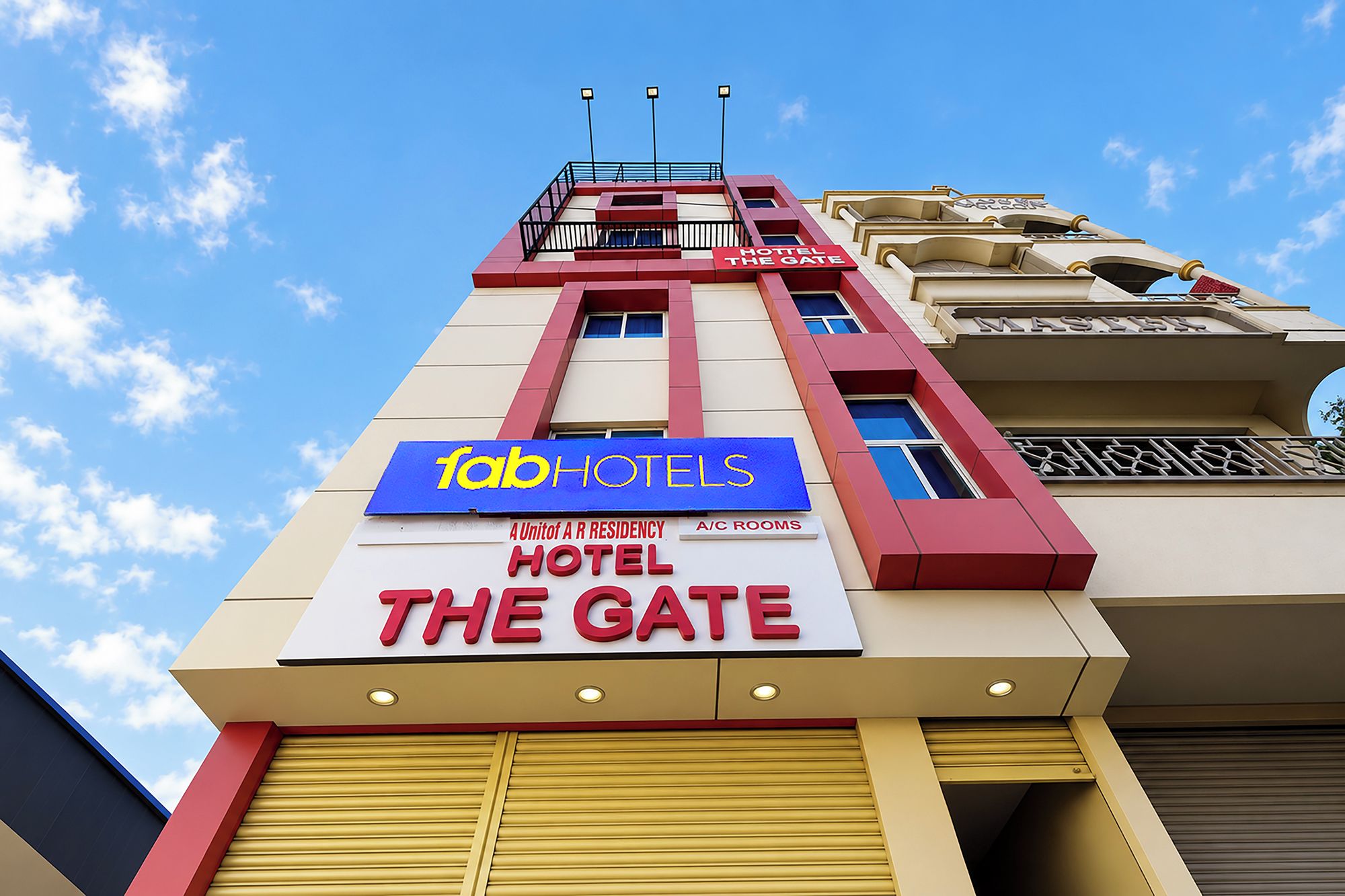 Une enseigne d’hôtel portant les marques « FabHotels » et « The Gate », indiquant qu’il s’agit d’un établissement du groupe A R Residency.