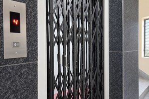 An elevator with a digital display showing the number 4, a metallic panel with a button, and a black metal gate.
