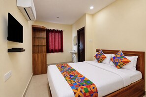 Una habitación de hotel con cama, televisión, armario, baño y puerta.