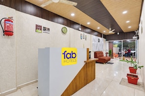 A hotel reception area with a reception desk, a fire extinguisher, and a clock on the wall. - Fabhotel The Urban Inn (Nagpur)