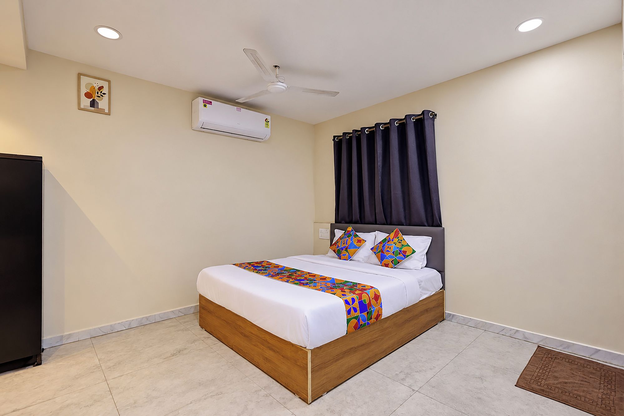 Quarto com cama, ventilador de teto, aparelho de ar condicionado e cortina escura.
