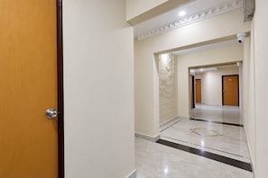 A hallway with a wooden door, a marble floor, and a wall with a decorative panel.