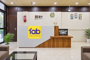 A reception desk with a logo, a clock, framed pictures, and a fire extinguisher.