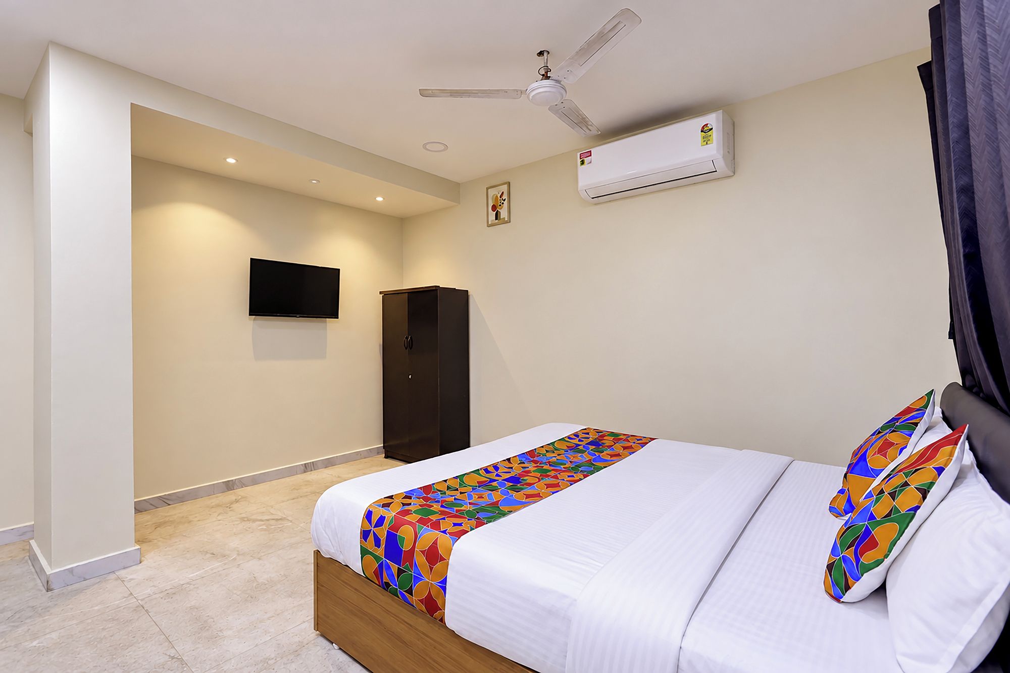 Una habitación de hotel con una cama, televisión, aire acondicionado y ventilador de techo.