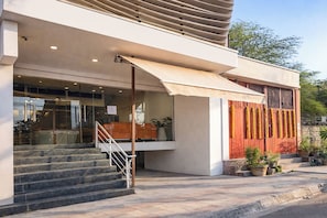 A modern building with a staircase leading to a glass entrance, outdoor seating area, and potted plants. - Fabhotel Orchid Blu (New Delhi)