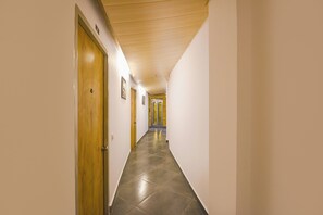 Un pasillo de hotel con puertas de madera, suelo de baldosas y techo inclinado.