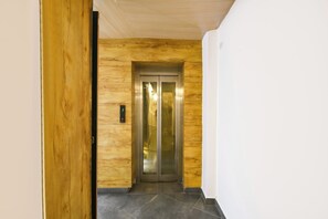 En gang med trævæg og dør til en glas elevator.