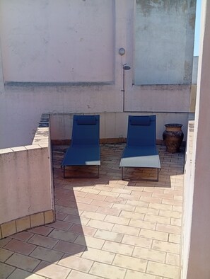 Eine Dachterrasse mit zwei Liegestühlen und einem großen Topf.
