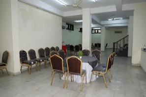 A conference room with a round table and chairs, a ceiling fan, and a staircase in the background.