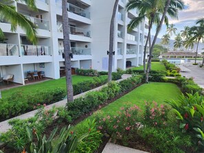 Ein Hotel mit mehreren Balkonen, einem gepflegten Garten mit verschiedenen Pflanzen und Blumen sowie Blick auf die umliegende Landschaft.