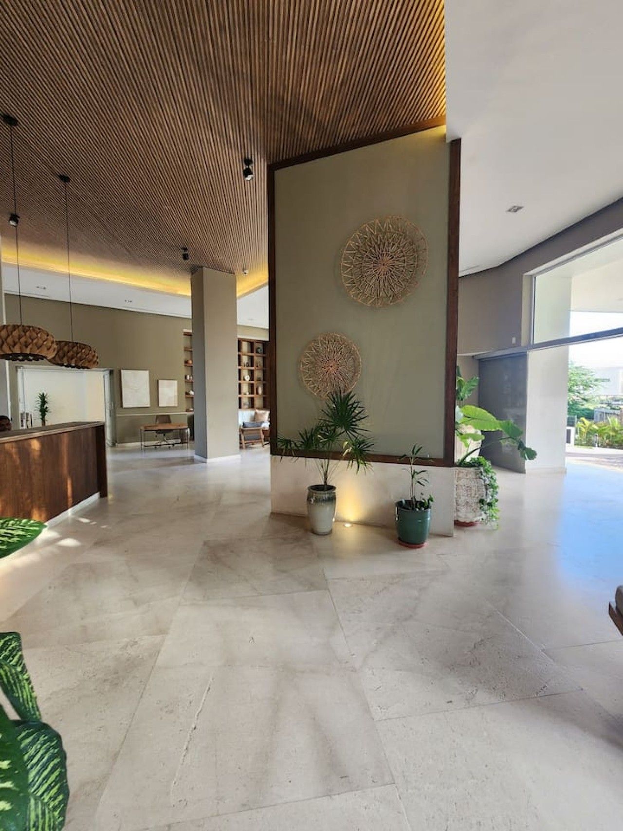 A spacious lobby with a reception desk, decorative wall art, and potted plants.