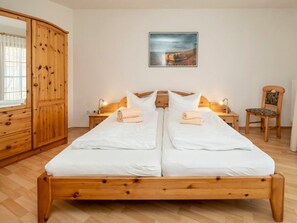 Ein Doppelbett mit weißer Bettwäsche, ein hölzerner Kopfseitenverkleidung, Nachttische mit Lampen, ein Holzschrank und ein gerahmtes Bild an der Wand.