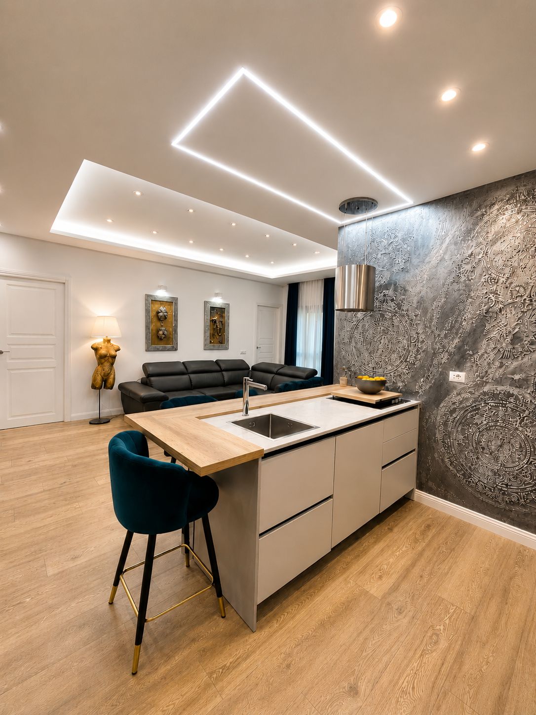 Cozinha moderna com ilha central, área de refeições com sofá e parede decorativa.