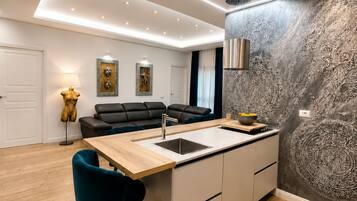Cozinha moderna com ilha central, área de refeições com sofá e parede decorativa.