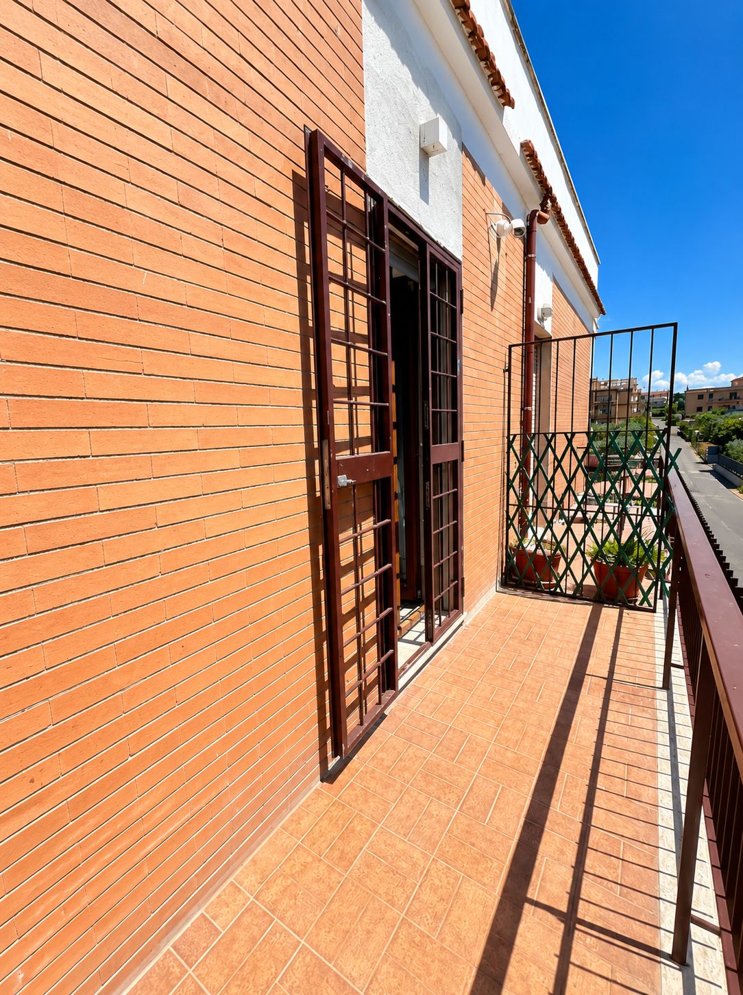 Un edificio con facciata in mattoni, cancello in metallo e balcone piastrellato.