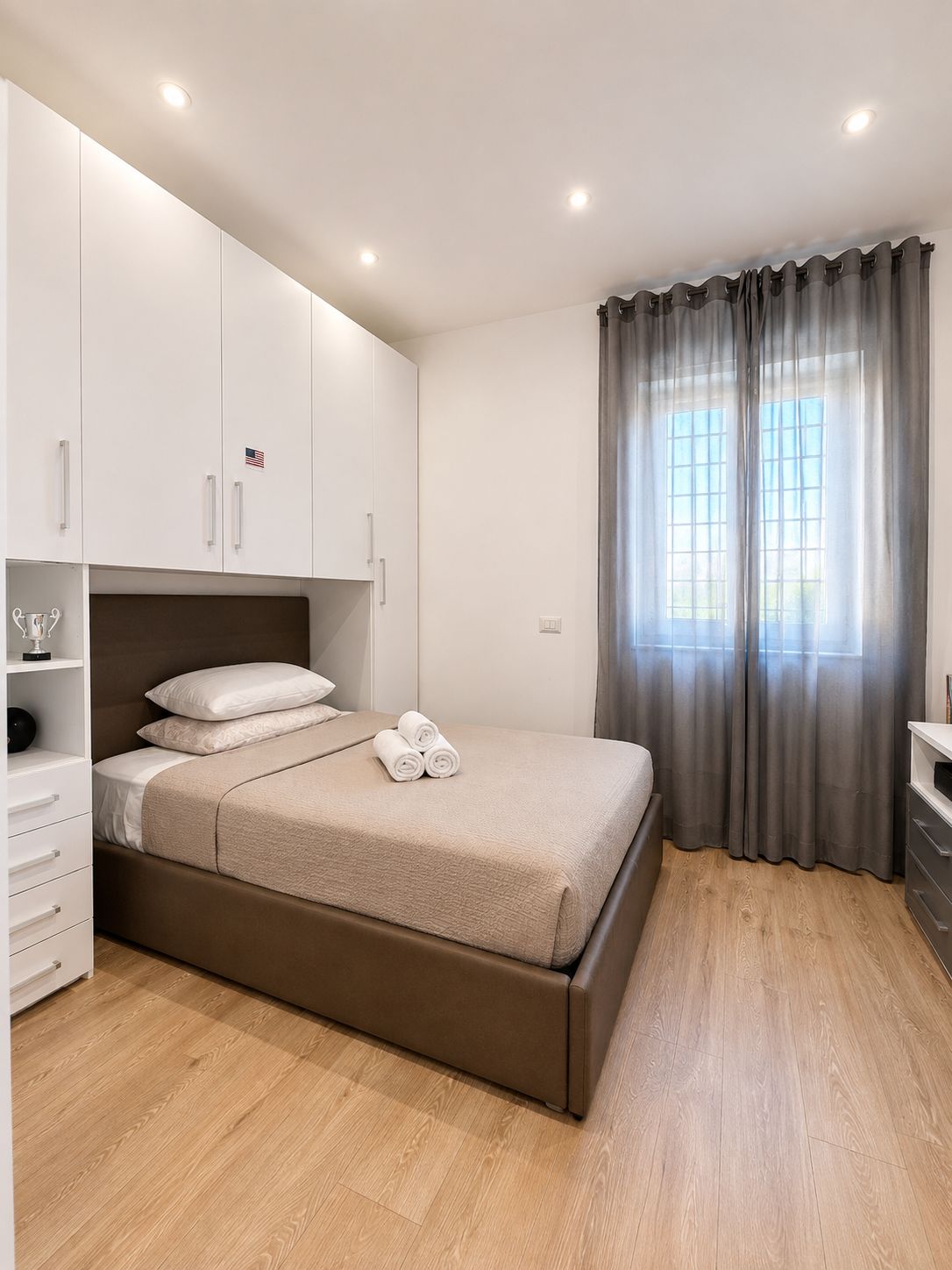 Ein modernes Schlafzimmer mit Bett, Einbauschrank und einem fenster mit Vorhängen.