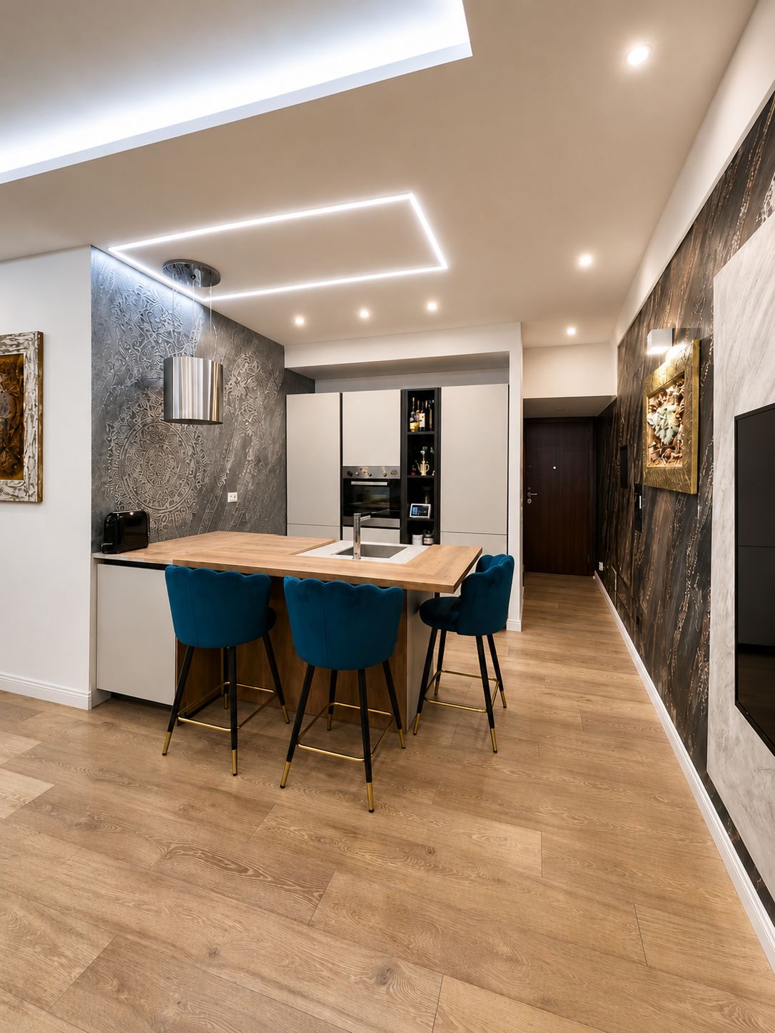 Eine moderne Küche mit Backofen und einer Essecke mit Holztisch und blauen Stühlen.